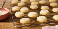 some cookies are cooling on a rack with a bowl of icing next to it