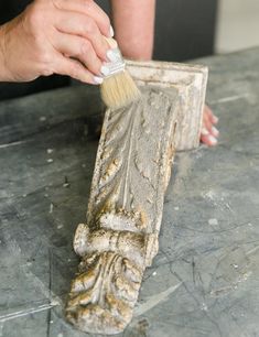 a person is using a brush to paint the base of a decorative object on a table