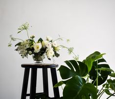 a vase with white flowers sitting on top of a table next to a potted plant