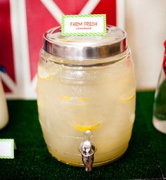 a glass jar filled with lemonade sitting on top of a table next to bottles