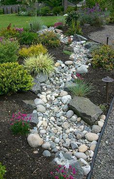 a garden with lots of rocks and flowers in the middle, along side a path