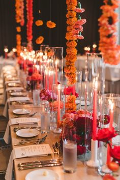 a long table is set with candles and flowers in vases, plates and silverware