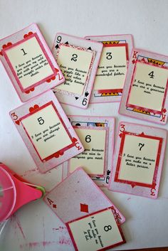 several cards with numbers on them sitting next to a pink cup filled with water and paper