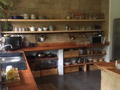 a kitchen filled with lots of wooden shelves next to a stove top oven and microwave