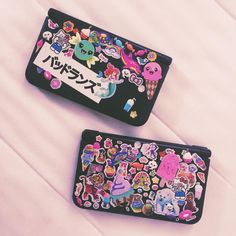 two black wallets with various stickers on them sitting next to eachother