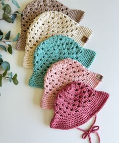 four crocheted bonnets are laying next to each other