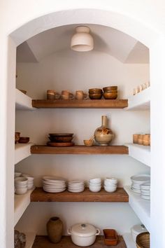 the shelves in this kitchen are filled with plates and bowls, pots and pans