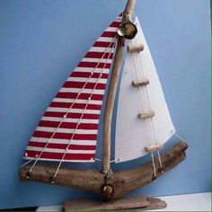 a wooden sailboat with red and white stripes on it's sails is sitting on a shelf