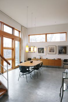 a dining room table and chairs in front of large windows