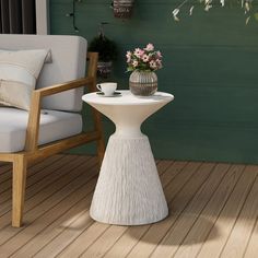 a white table sitting on top of a wooden floor next to a chair and potted plant