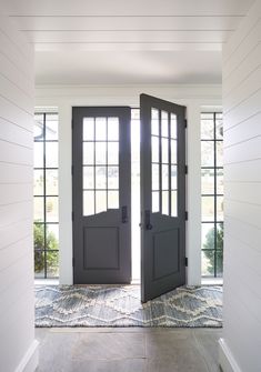 an open door leading to another room with two windows on each side and carpeted floor