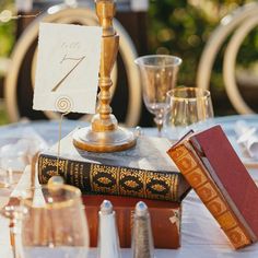 a table topped with books and glasses filled with wineglasses on top of a white table cloth