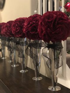 red flowers in vases lined up on a shelf