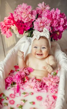 a baby sitting in a tub with pink flowers