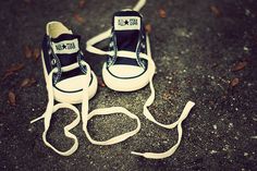 two pairs of black and white tennis shoes on the ground with one shoe tied up