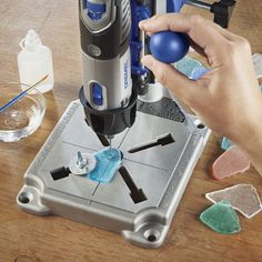 a person using a driller on a piece of wood with various tools around it