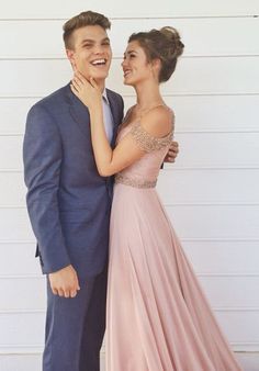 a young man and woman standing next to each other in front of a white wall