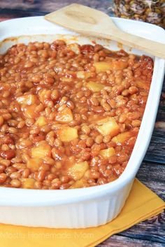 a white dish filled with baked beans and pineapple