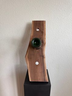 a wooden object on top of a black stand with a green glass in the middle