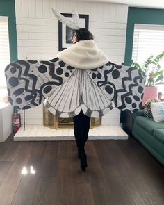 a woman in a white and black dress is walking through a room with a fireplace