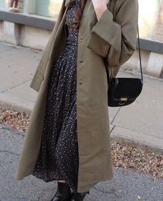 a woman is standing on the sidewalk talking on her cell phone and holding a purse