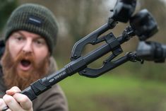 a man with a beard is holding an outdoor device in his hand and looking at the camera