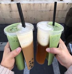 two people holding up drinks with straws in their hands, and one is green