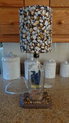 a bottle lamp sitting on top of a counter next to some jars and containers filled with nuts