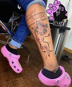 a woman's legs with pink clogs and flowers on her leg, while sitting