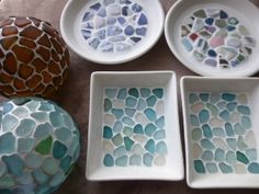 four bowls with different designs on them sitting next to two vases and one bowl