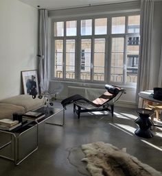 a living room filled with furniture next to a large window covered in windowsills