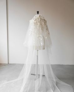 a wedding dress on a mannequin wearing a veil with flowers and leaves attached to it