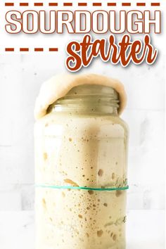 a jar filled with liquid sitting on top of a white counter next to a sign that says sourdough starter