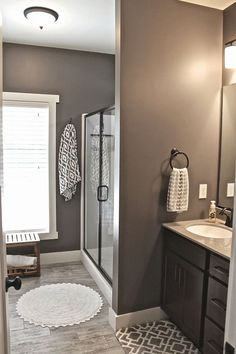 a bathroom with gray walls and white rugs on the floor, along with a walk in shower