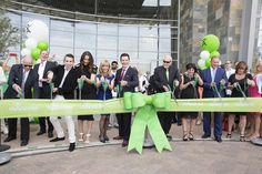 a group of people standing behind a green ribbon