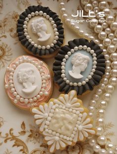 four decorated cookies on a plate next to pearls and necklaces with the words julia's sugar collection