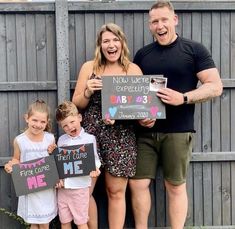 a man and two children holding up signs with the words now we're expecting