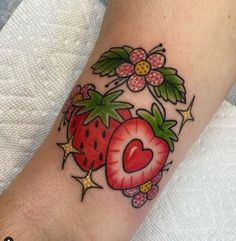 a strawberry tattoo on the left arm with a heart and leaves around it's center