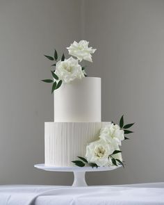 a three tiered cake with white flowers on top