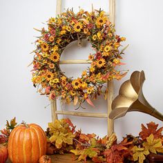 an arrangement of fall decorations including a wreath, trumpet and pumpkins