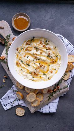 a white bowl filled with cheese and crackers next to some dipping sauce on the side