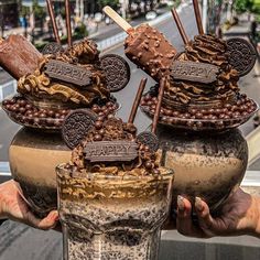 a person holding up an ice cream sundae in front of a cityscape