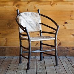 a wooden chair sitting on top of a wooden floor next to a wood paneled wall