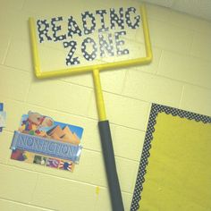 a yellow sign that reads reading zone next to a bulletin board with writing on it