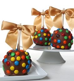 three chocolate covered desserts with bows on them sitting on white platters, ready to be eaten