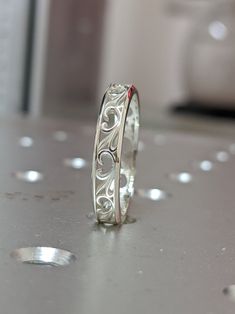 two wedding bands sitting on top of a table next to each other, one with an intricate design in the middle