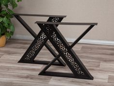 a black metal table sitting on top of a wooden floor next to a potted plant