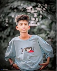 a young boy standing with his hands on his hips and looking at the camera while wearing a blue shirt