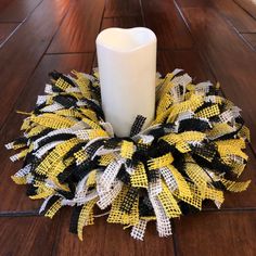 a yellow and black wreath with a white candle