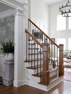 the stairs in this house are made of wood and wrought iron railings, along with potted plants